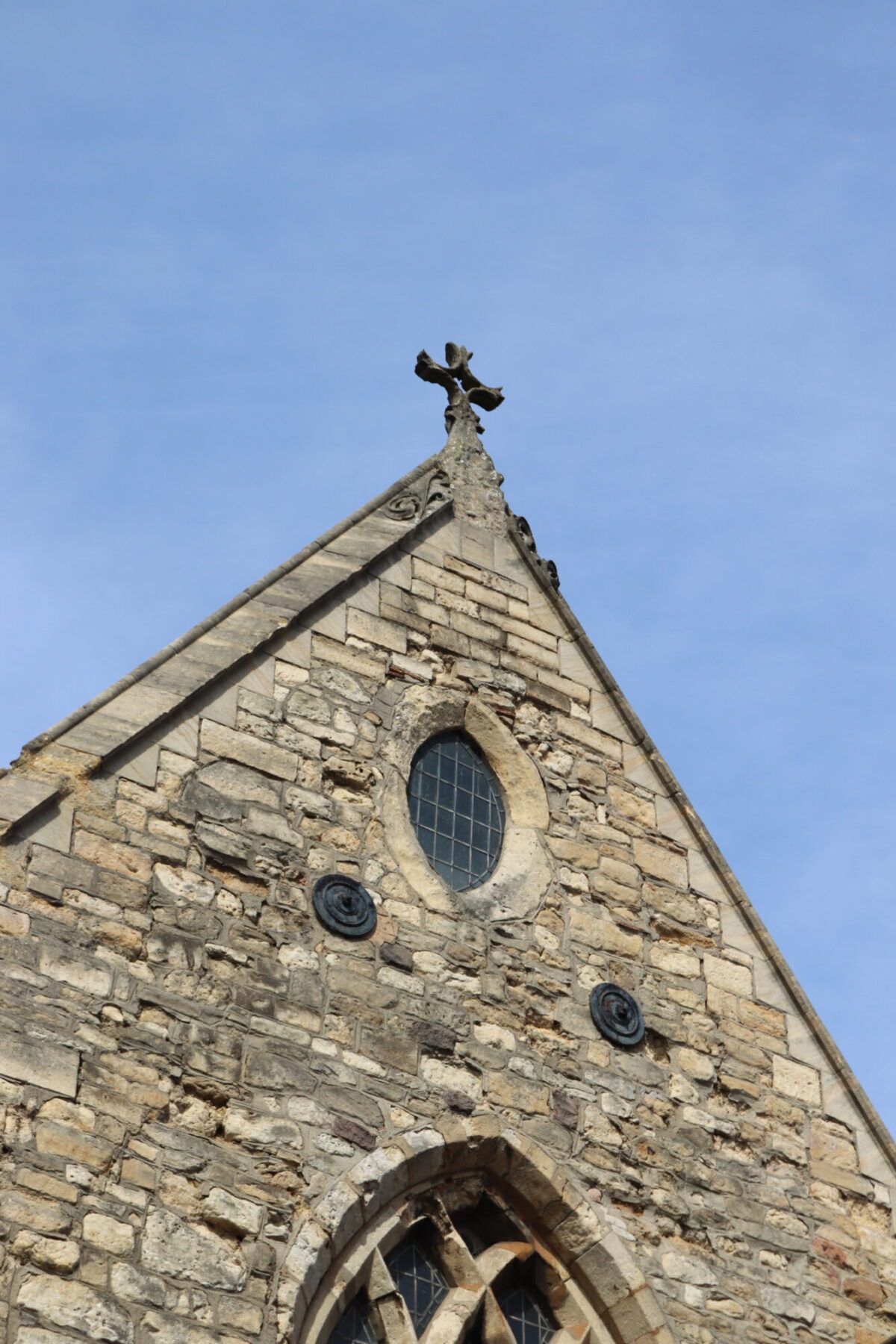Gable end of the Greyfriars building with an oval shaped window and stone cross on the point of the roof.