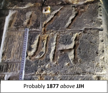 Photo of graffiti carved into stone. Text reads, "Probably 1877 above J J H".