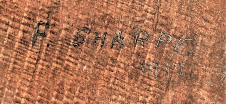 Close up image of carved graffiti spelling F SHARPE 1917.