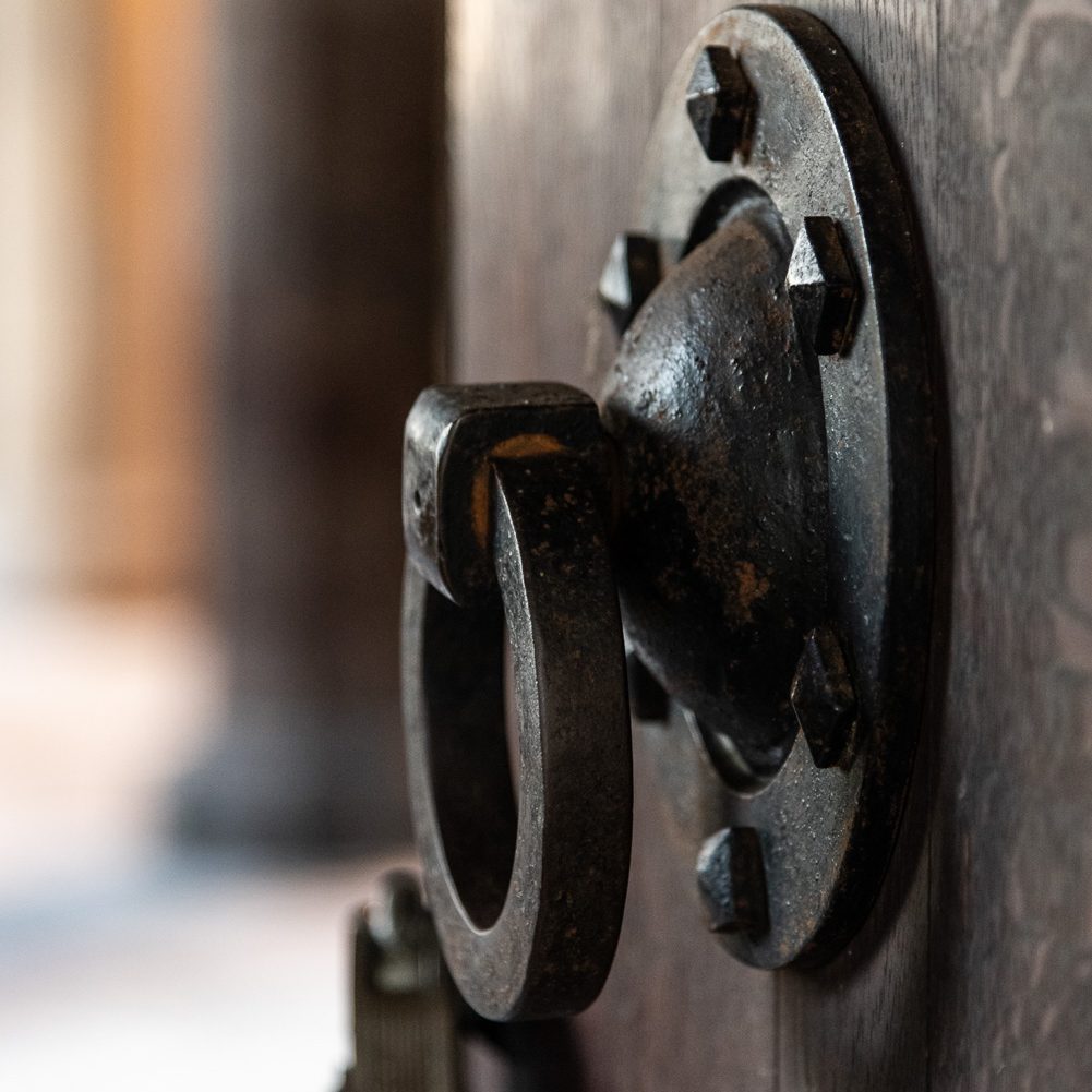 Large iron door knocker affixed to a wooden door.
